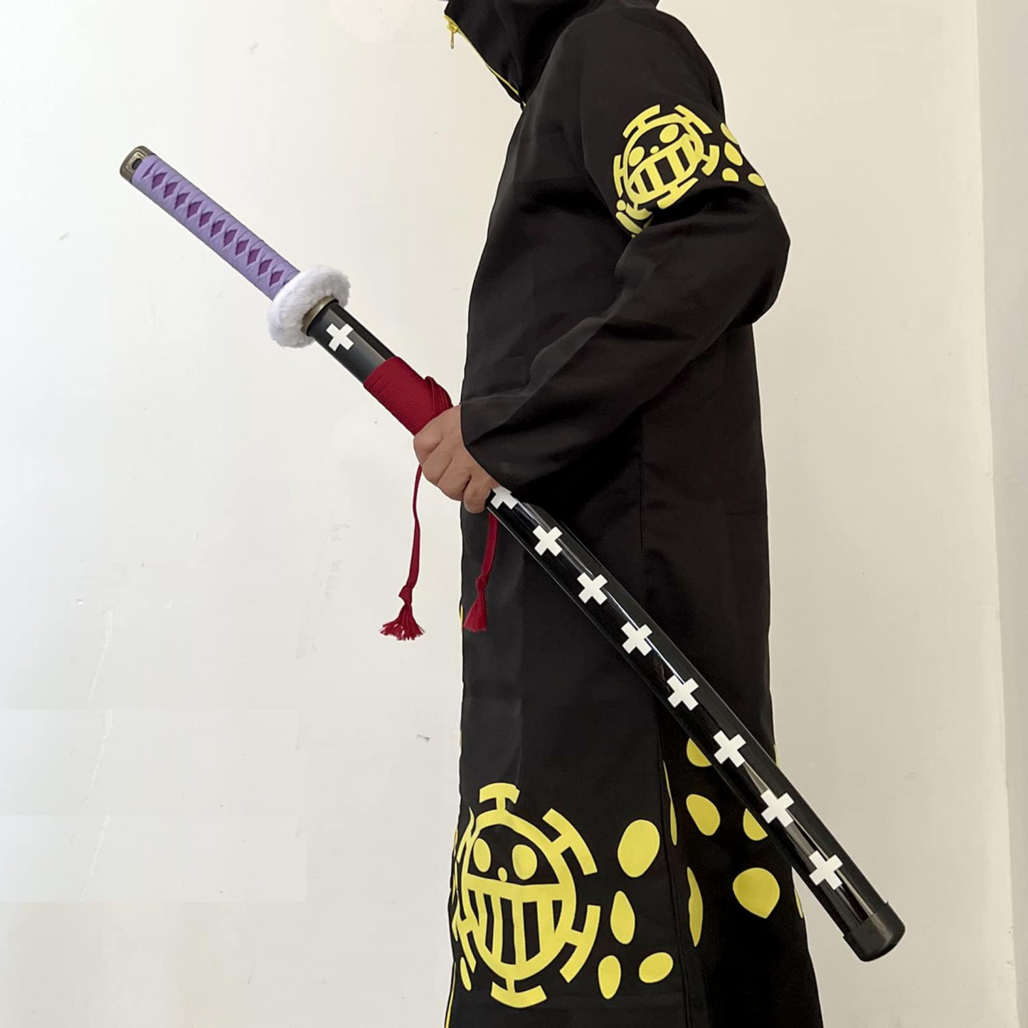 Trafalgar D. Law Kikoku Wooden Katana with purple handle, white guard, and black sheath featuring white crosses, displayed on a wooden stand