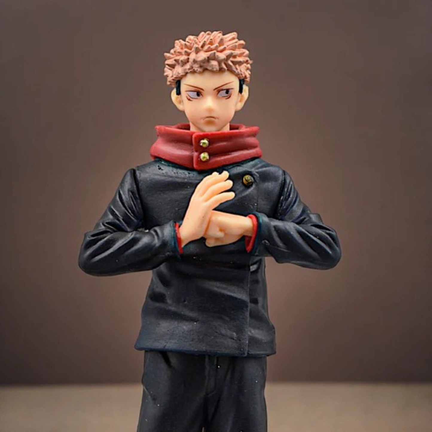 Jujutsu Kaisen Itadori Yuji action figure in school uniform with red hoodie, standing on a display base against a red-dark background