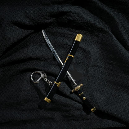 Black and gold Yubashiri katana keychain inspired by One Piece's Roronoa Zoro, placed on a dark fabric background