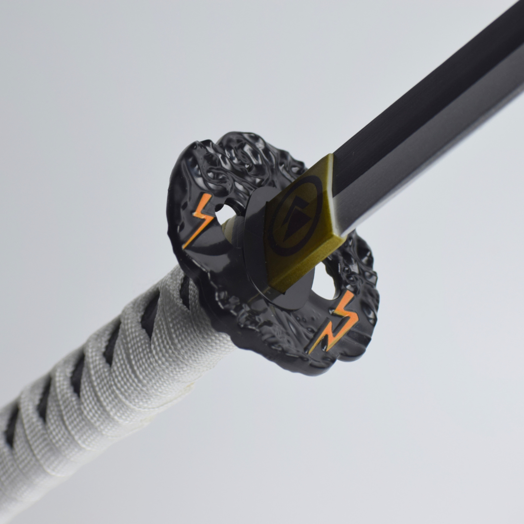 Ghost of Tsushima: Jin Sakai Wooden Katana 104cm - close-up of the black tsuba with orange lightning and the gold Sakai crest